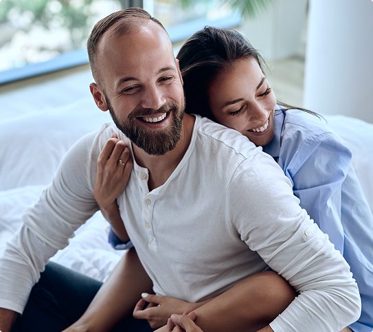 Smiling couple embracing affectionately together in bed